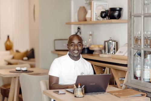 a man sitting at a table with a laptop at Cape Finest Guest House located in De Waterkant in Cape Town