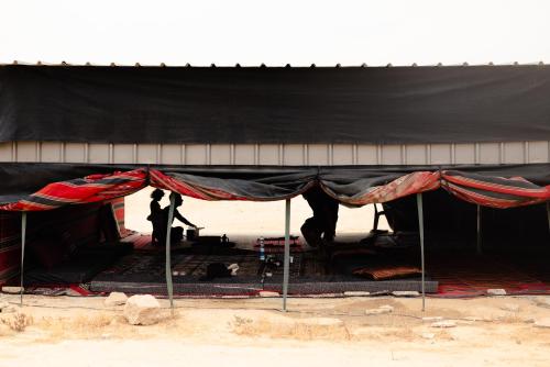 two people standing inside of a black tent at אוהל בוסתן הזיתים in Midreshet Ben Gurion