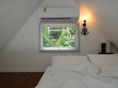 a bedroom with a white bed and a window at RaftDara Erawan Resort in Tha Kradan