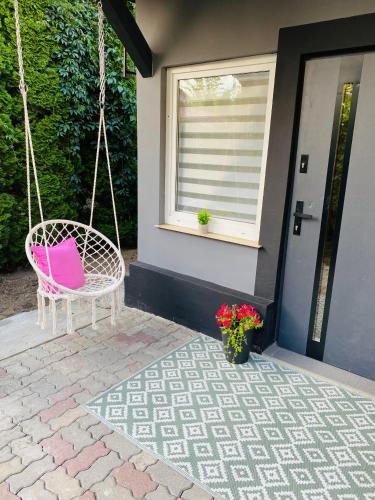a pink swinging chair in front of a house at Apartamenty pod wieżą 2 in Olsztynek