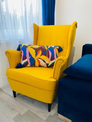 a yellow chair with a colorful pillow in a room at Apartamenty pod wieżą 2 in Olsztynek