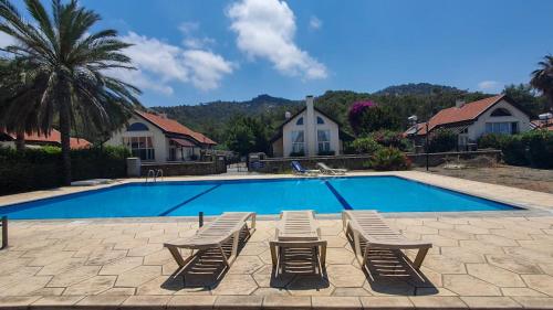 a swimming pool with four lounge chairs and a swimming pool at Harmony Homes in Kérynia