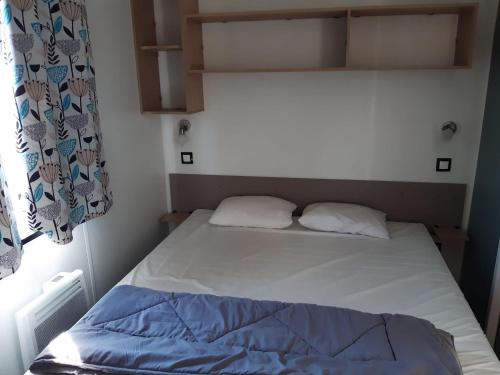 un letto in una piccola camera con due cuscini di Bungalow M027 chez D&D a Torreilles