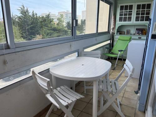 une table et des chaises blanches devant une fenêtre dans l'établissement Appartement T2 entre plage et commerces, loggia, parking privé, proche pistes cyclables - FR-1-324A-60, à Saint-Hilaire-de-Riez