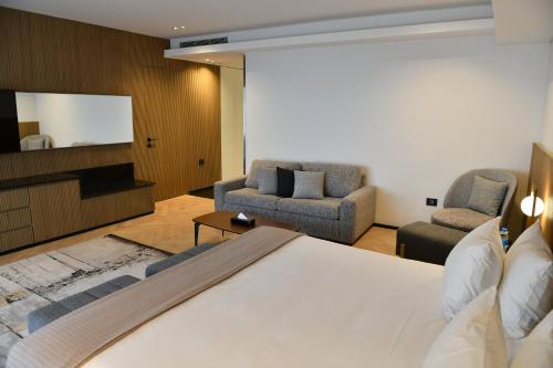 a bedroom with a bed and two chairs and a television at Faqra Hills Hotel in Kfardebian