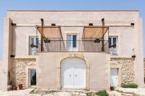 an old house with a balcony and a white door at Casale Micale in Noto