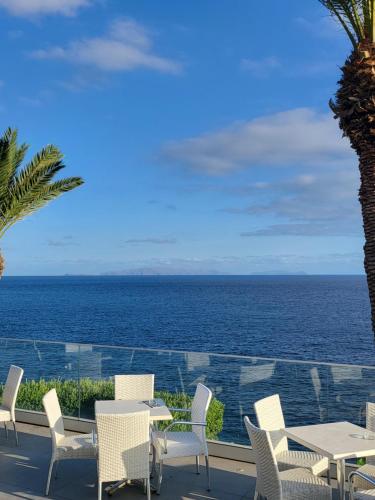 a patio with tables and chairs and the ocean at Hotel Roca Mar in Caniço