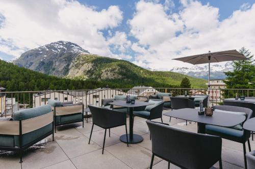 a patio with tables and chairs with mountains in the background at Sunstar Pontresina in Pontresina