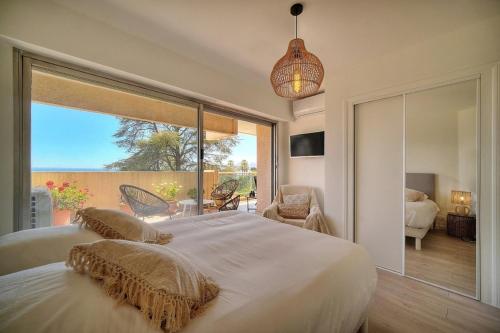 une chambre avec un grand lit et une grande fenêtre dans l'établissement A2B232 Bel appartement vue mer et proche plage, à Cannes