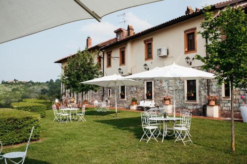 an outdoor patio with tables and chairs and umbrellas at Glass Apartment Tenuta il Galletto in Casale Monferrato