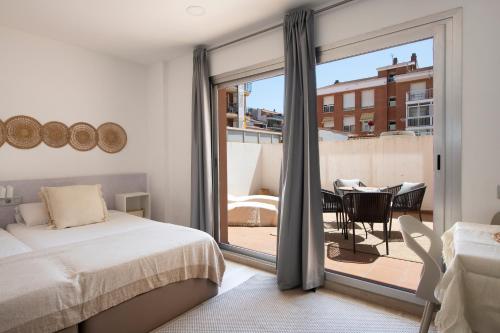a bedroom with a bed and a balcony with a table at Aparthotel Centric in Castelldefels