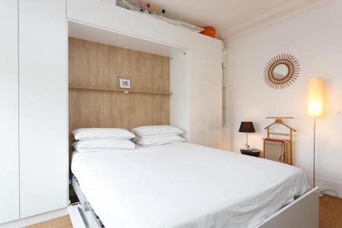 une chambre avec un lit blanc avec une tête de lit en bois dans l'établissement High standing Studio Paris 17, à Paris