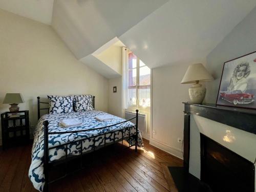 a bedroom with a bed and a fireplace and a window at Maison de caractere cœur du village 1h de Paris in Montigny-sur-Loing