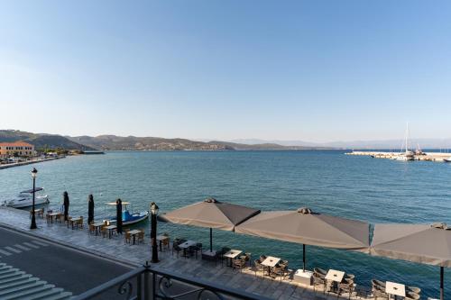 a view of a body of water with tables and umbrellas at YeeOn Living-Well Boutique City Hotel Gythio in Gythio