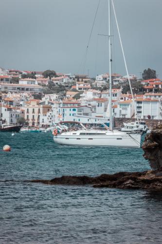 a white sail boat in the water near a city at Hotel Boutique Es Blau in Cadaqués