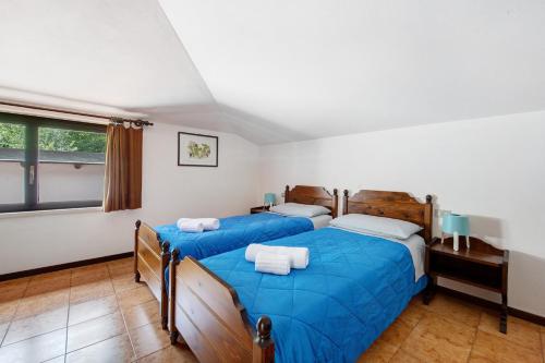 a bedroom with two beds with blue sheets and a window at Appartamento Rupestre 2.0 in Manerba del Garda
