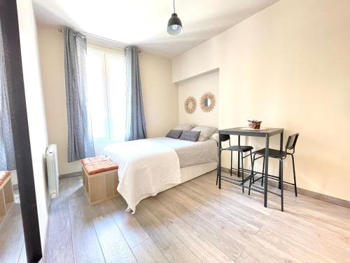 une chambre avec un lit, une table et des chaises dans l'établissement Studio neuf à 2 pas du métro, aux Lilas