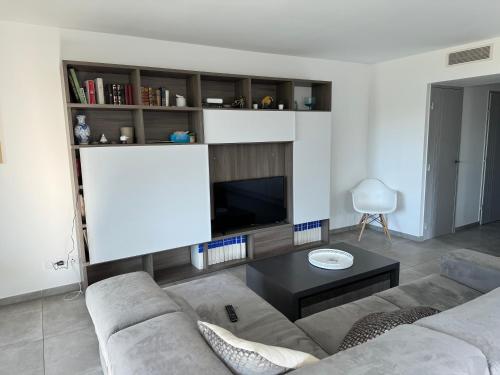 un salon avec un canapé et une télévision à écran plat dans l'établissement T3 NEUF AVEC TERRASSE ET JARDIN FACE a LA MER, à Bandol
