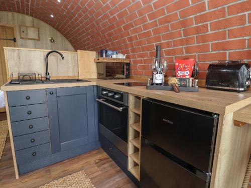 a kitchen with a black dishwasher and a brick wall at Rhosydd in Ruthin