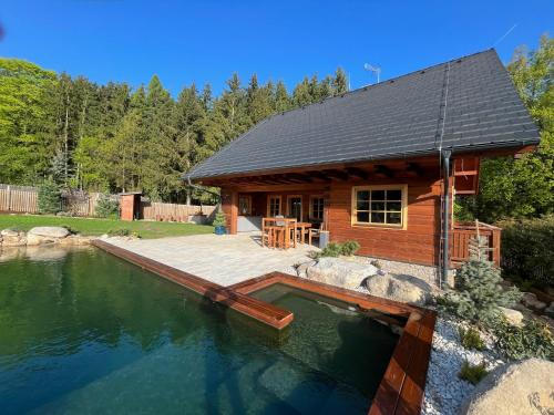 a log cabin with a swimming pool in front of it at Roubenka Kamennka in Borotín