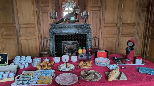 une table avec un tissu de table rouge et de la nourriture dans l'établissement Château de Beauchamp en Sarthe, à Villaines-la-Gonais