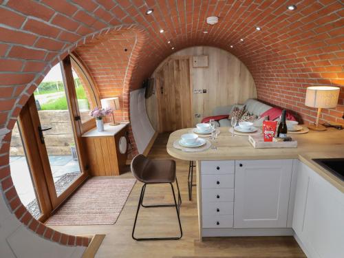 a kitchen with a brick wall and a table at Weirglodd in Ruthin