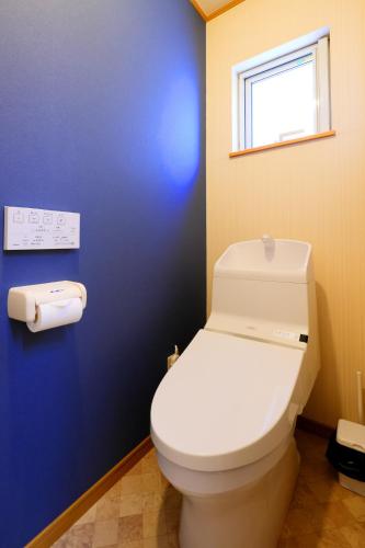 a white toilet in a bathroom with a blue wall at Rose Garden in Asahikawa
