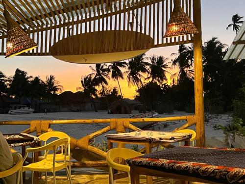 a patio with tables and chairs and a view of the beach at Malcom Ocean View Retreat in Pongwe