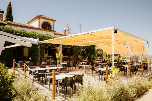 a restaurant with tables and chairs under a yellow umbrella at Escua in Archidona