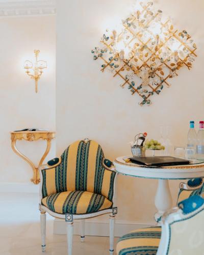 a room with two chairs and a table with a chandelier at Hotel Villa e Palazzo Aminta in Stresa