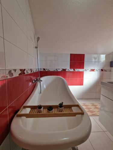 une baignoire blanche dans une salle de bain rouge et blanche dans l'établissement Vila av lugnet, à Kobiljača