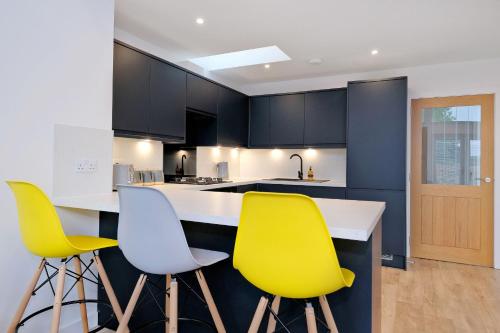 a kitchen with yellow and white chairs and a counter at Contemporary Luxury Lodge, Aberdeen West in Blackburn