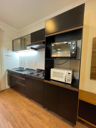 a kitchen with a microwave and a stove top oven at Residencial Luce Del Sole - Apto Nº 2 in Joinville