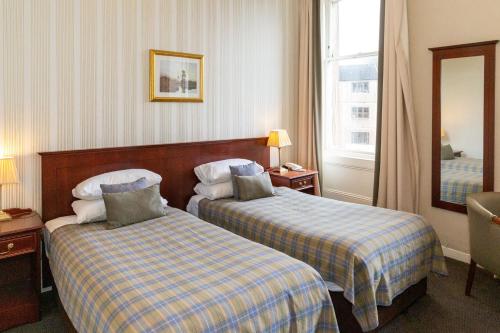 a hotel room with two beds and a mirror at The Royal Hotel in Oban