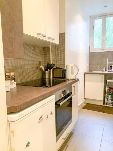 une cuisine avec des armoires blanches et un comptoir dans l'établissement Studio de charme Tour Eiffel, à Paris