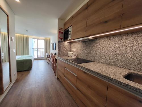 a kitchen with a sink and a bed in a room at Hotel Royal Orchid in Caniço