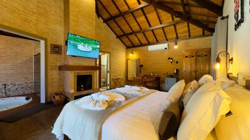 a bedroom with a large bed and a tv at Flores da Mantiqueira in Monte Verde