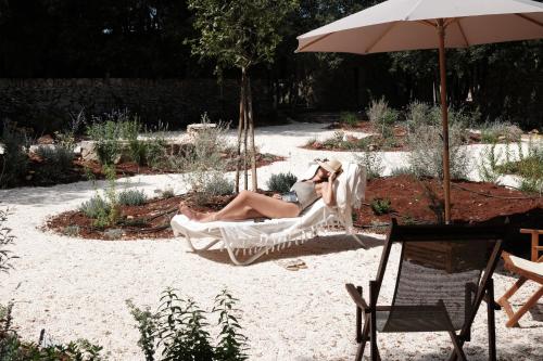 a woman sitting in a hammock in a garden at Agriturismo Iazzo Scagno in Martina Franca