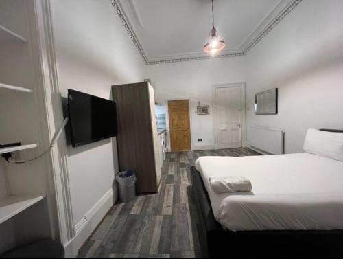 a hotel room with a bed and a flat screen tv at Queens Park Studio in Glasgow