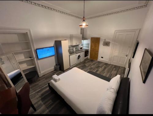a bedroom with a white bed and a kitchen at Queens Park Studio in Glasgow