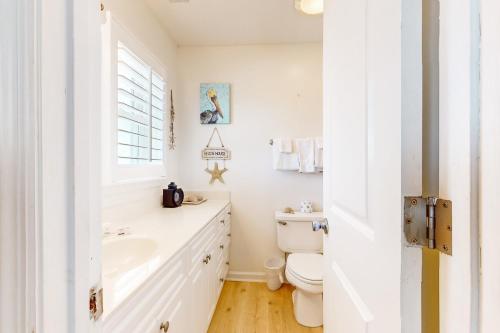 a white bathroom with a sink and a toilet at Queen B in Holden Beach