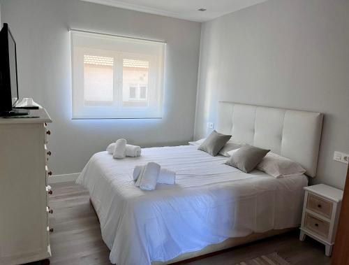 a white bed in a bedroom with a window at La Casa del Minero in Olleros de Sabero