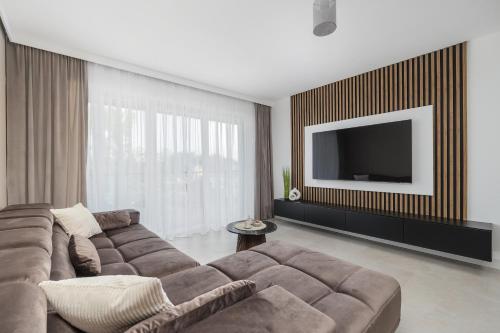 a living room with a couch and a flat screen tv at Exclusive Apartments Porta Mare Marina - Swimming Pool & Sauna by Renters Prestige in Dziwnów