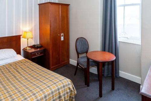 a bedroom with a bed and a table and a chair at The Royal Hotel in Oban
