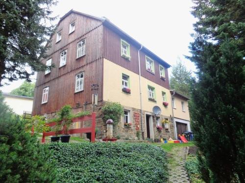 a large brick building with white windows and bushes at Pension Kaufmann Ferienwohnung "Wolke 7" in Oberwiesenthal