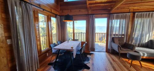 uma sala de jantar com uma mesa e algumas janelas em A Cabana do Norueguês em Urubici