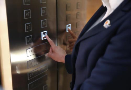 a woman is pointing to an elevator button at Holiday Inn Express Zhengzhou Zhongzhou by IHG in Zhengzhou