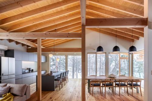 a kitchen and dining room with wooden ceilings and a table and chairs at Villa Aoi in Hakuba