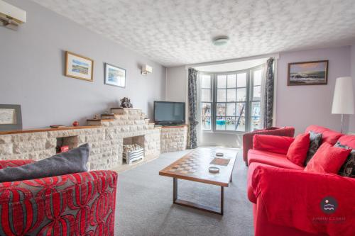 a living room with two red chairs and a fireplace at 14 Nothe Parade - Waterfront Holiday Cottage in Weymouth