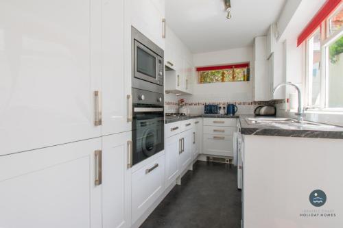 a white kitchen with a sink and a stove at 14 Nothe Parade - Waterfront Holiday Cottage in Weymouth